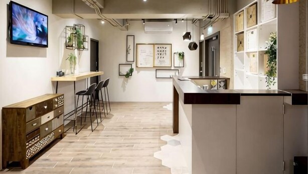A modern kitchen with a wooden floor, bar stools, a long counter, and a TV mounted on the wall. - 109 Inn Taipei (Taipei City)