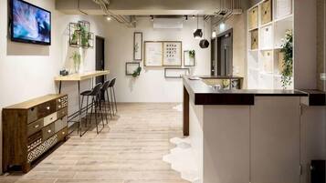 A modern kitchen with a wooden floor, bar stools, a long counter, and a TV mounted on the wall.