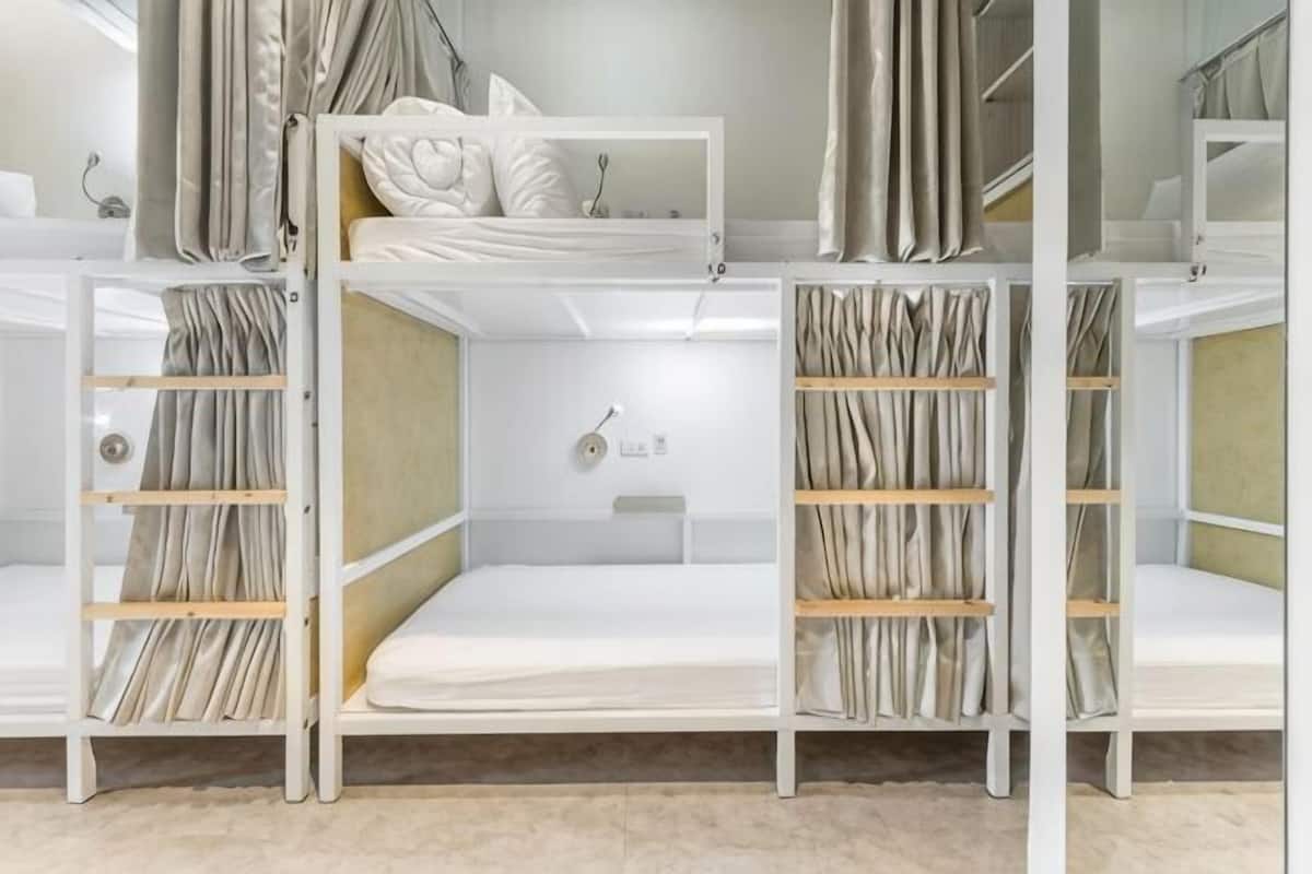 Bunk beds with curtains, a small shelf, and a wall-mounted light fixture.