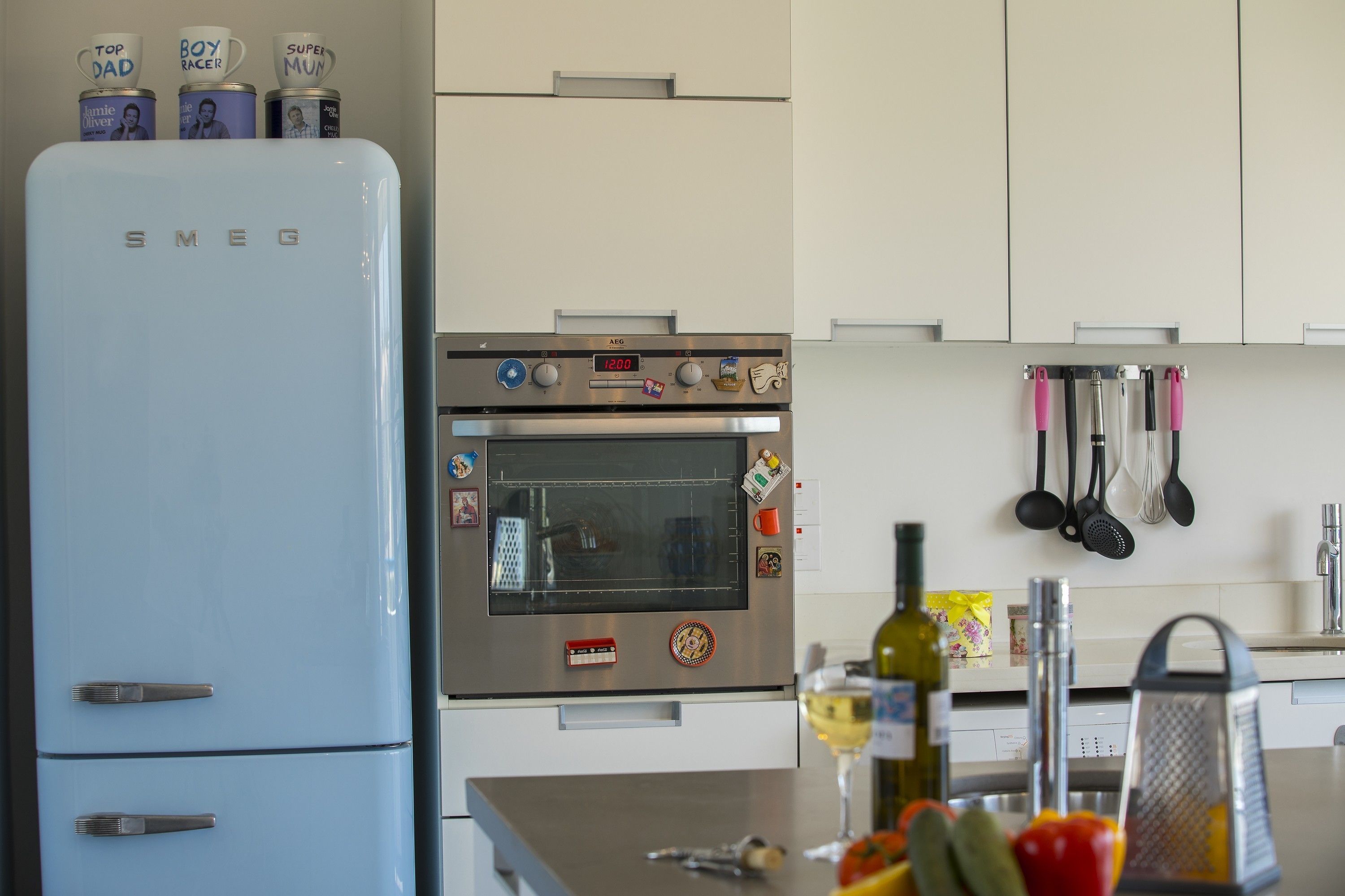 A kitchen with a blue refrigerator, an oven, and various kitchen utensils.