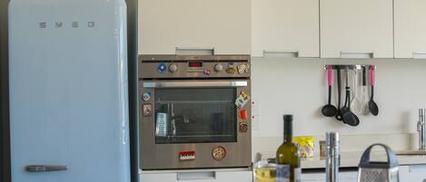 A kitchen with a blue refrigerator, an oven, and various kitchen utensils.