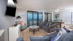 A living room with a sofa, a coffee table, and a dining area with chairs and a table.