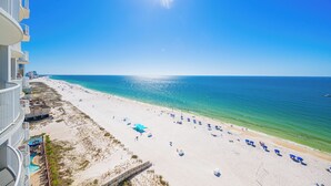 Una playa con cielo despejado, piscina y un edificio con balcones.