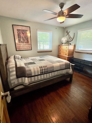 A bedroom with a bed, a ceiling fan, a dresser, a framed poster, and a window with blinds. - Lakefront Home and Dock with Tiki Bar At 4mm at Lake Of The Ozarks! (Rocky Mount)