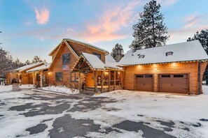 Cozy cabin with a welcoming front porch, complete with a festive wreath and string lights.