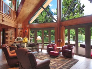 Enjoy expansive views of the surrounding greenery and water from the large windows in this inviting room.