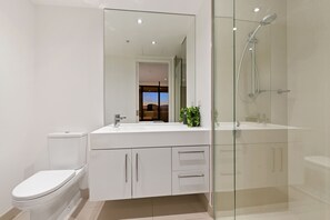 A modern bathroom with a glass-enclosed shower, a white sink, and a toilet.