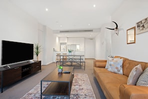 Relax in this stylish living room with a flat-screen TV, comfortable sofa, and dining area.