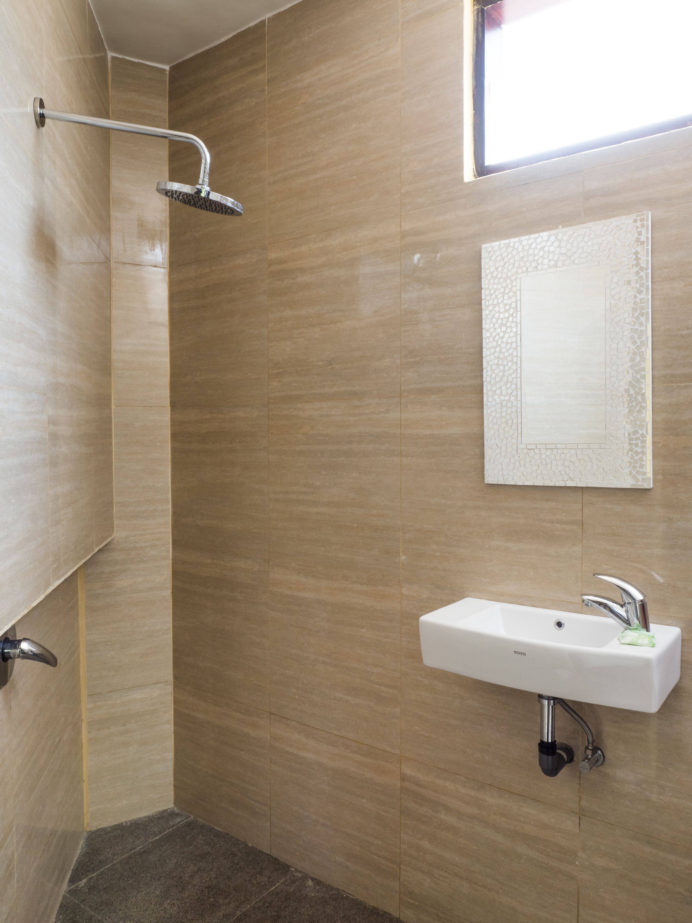 Un baño moderno con ducha, lavamanos y un espejo decorativo.
