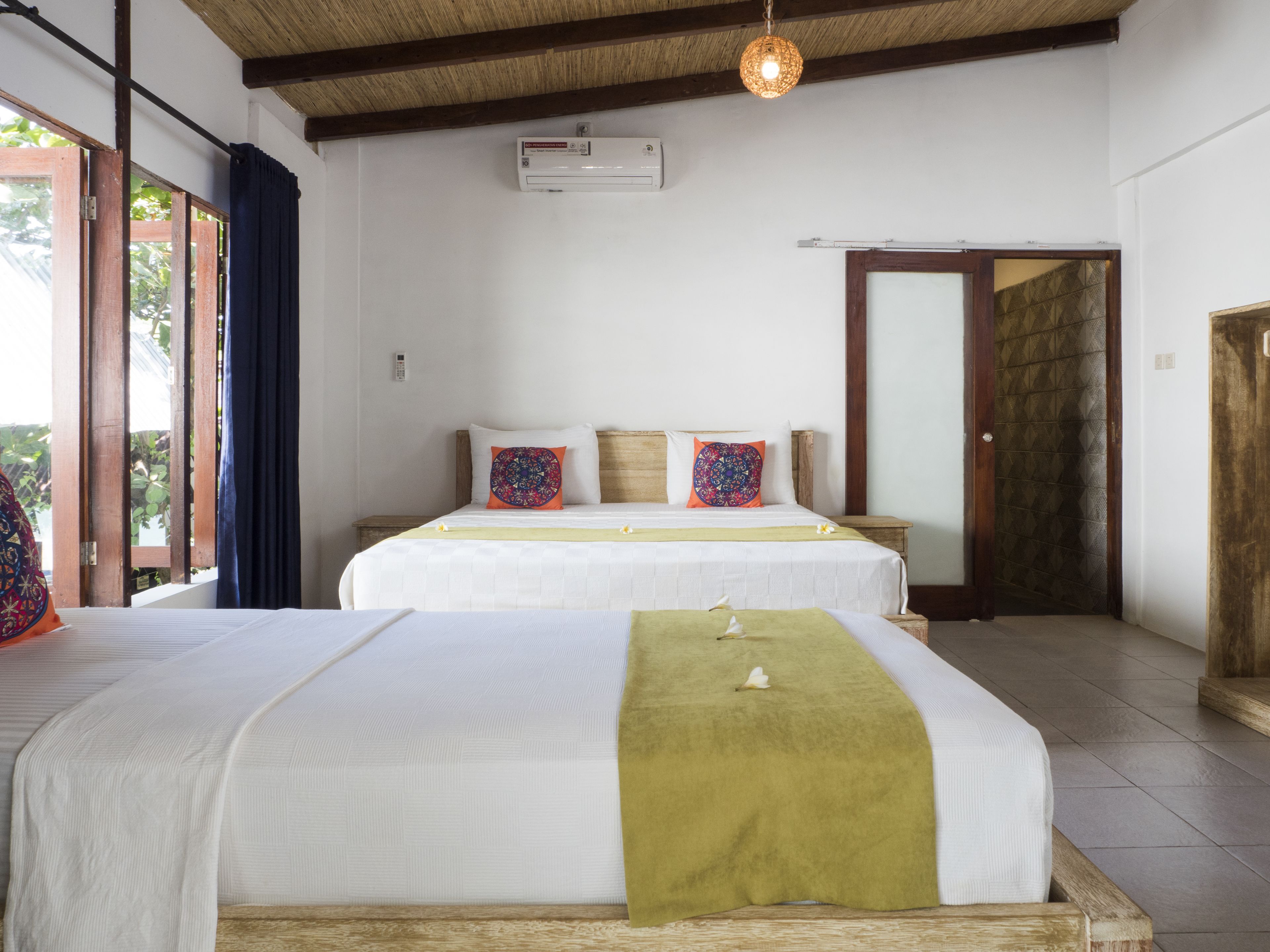 Une chambre double avec deux lits, un plafond en bois et une grande fenêtre avec des rideaux.