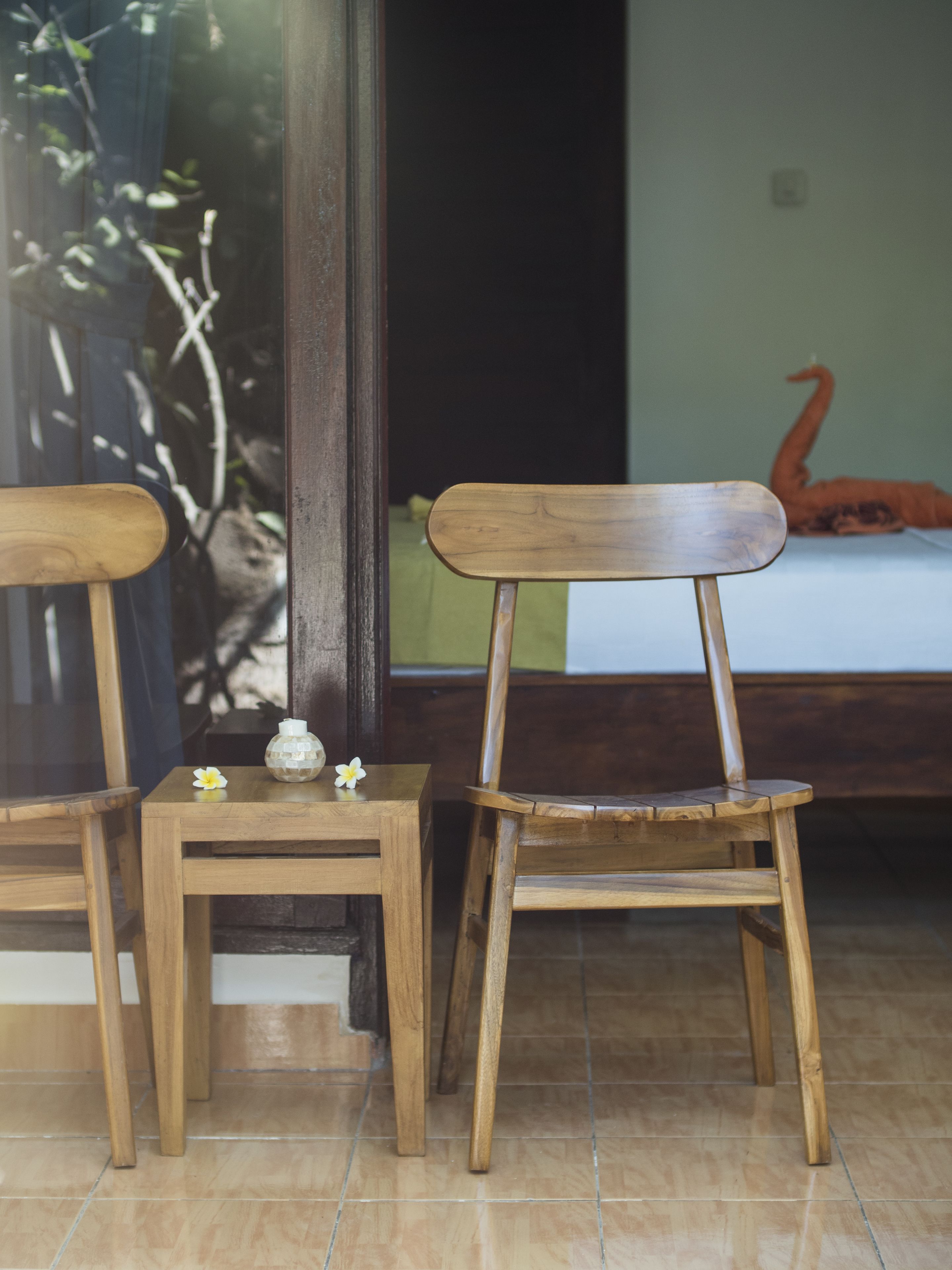 Two wooden chairs and a small table with a decorative item and a flower.
