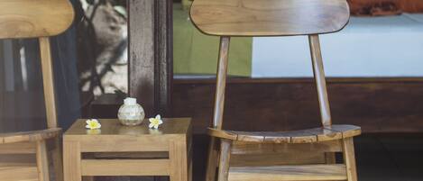 Two wooden chairs and a small table with a decorative item and a flower.