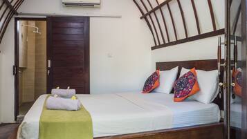 Un dormitorio con estructura de cama de madera, ropa de cama blanca y almohadas coloridas.