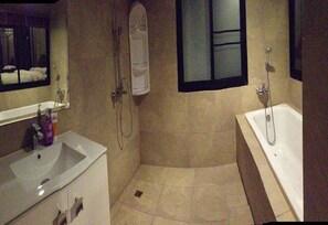 Une salle de bain avec une baignoire, une douche et un lavabo.