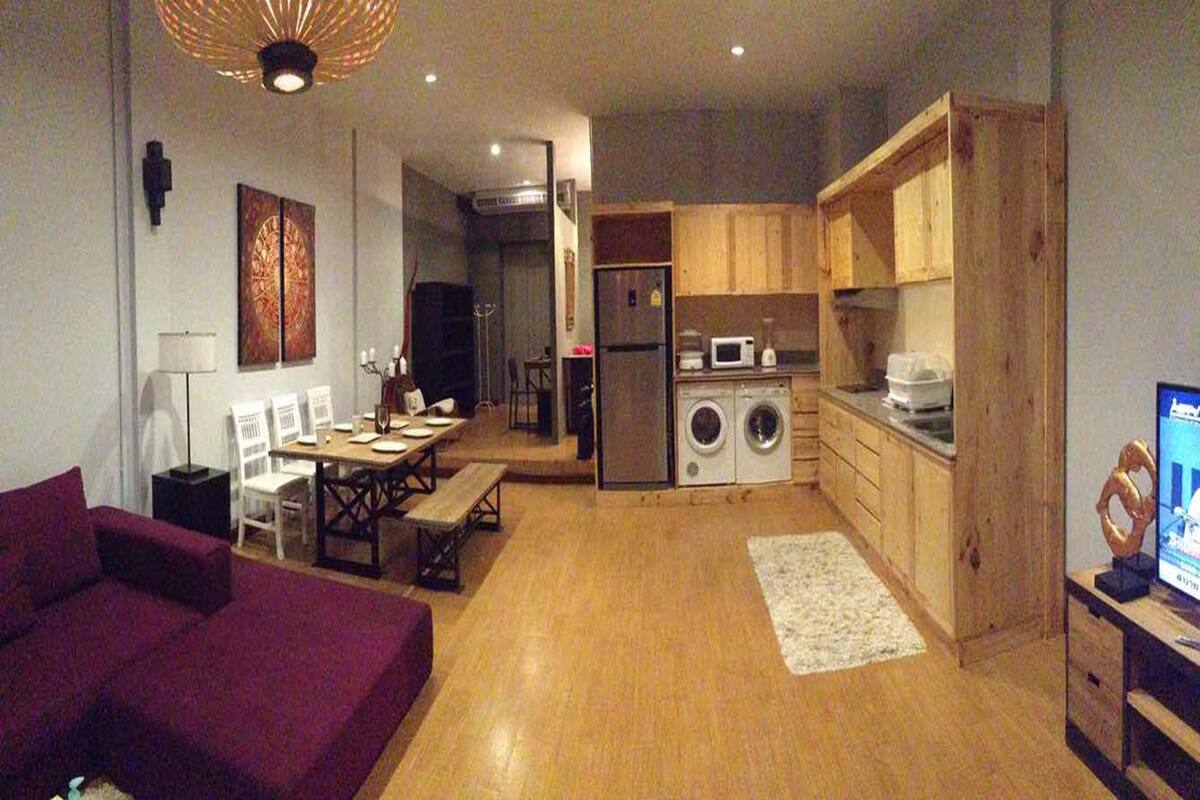 Un espace de vie compact comprenant un coin repas, un canapé, un lave-linge et un téléviseur.