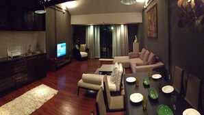 Una sala de estar moderna con comedor, pisos de madera y televisor.