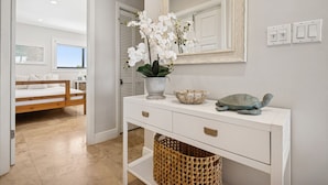 Une salle de bain moderne avec un meuble-lavabo blanc, un grand miroir, une orchidée en pot, un bol en céramique et une tortue décorative.