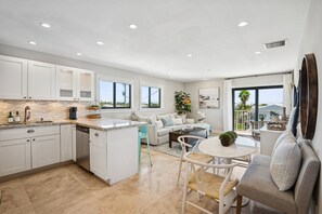 Une cuisine moderne avec des meubles blancs, un îlot central et un coin repas comprenant une table ronde et des chaises.