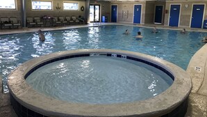 An indoor swimming pool with a hot tub in the center, surrounded by blue doors and windows. - Southern Comfort! Ground Floor, Impeccably Maintained....Indoor & Outdoor Pools (Gulf Shores)