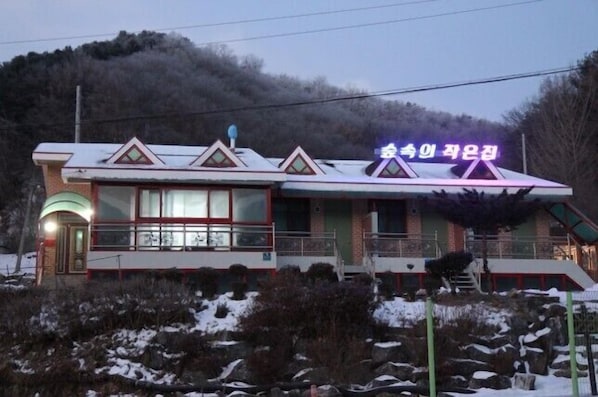 A building with a snow-covered roof and a neon sign in Korean. - Small House Wood (Chuncheon)