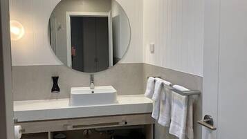 Un baño moderno con un espejo redondo, un lavabo blanco y un perchero para toallas.