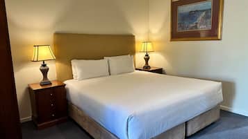 A neatly made bed with white linens and two bedside lamps.