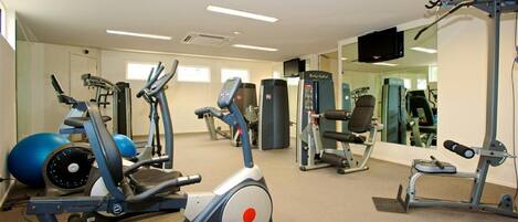 A gym with cardio machines, weightlifting equipment, and a mirrored wall.