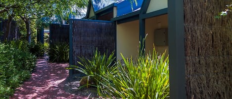 A pathway leading to a building with a blue roof and a covered area.