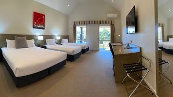 A hotel room with four beds, a desk, and a large mirror.