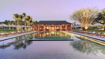 Um hotel com piscina, espreguiçadeiras e guarda-sóis.