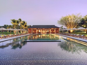 A hotel with a swimming pool, lounge chairs, and umbrellas. - Legacy Mekong, Can Tho, Autograph Collection (Can Tho)