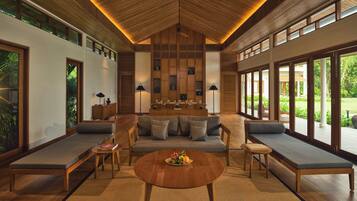 A spacious living area with a wooden ceiling, large windows, and a central coffee table.