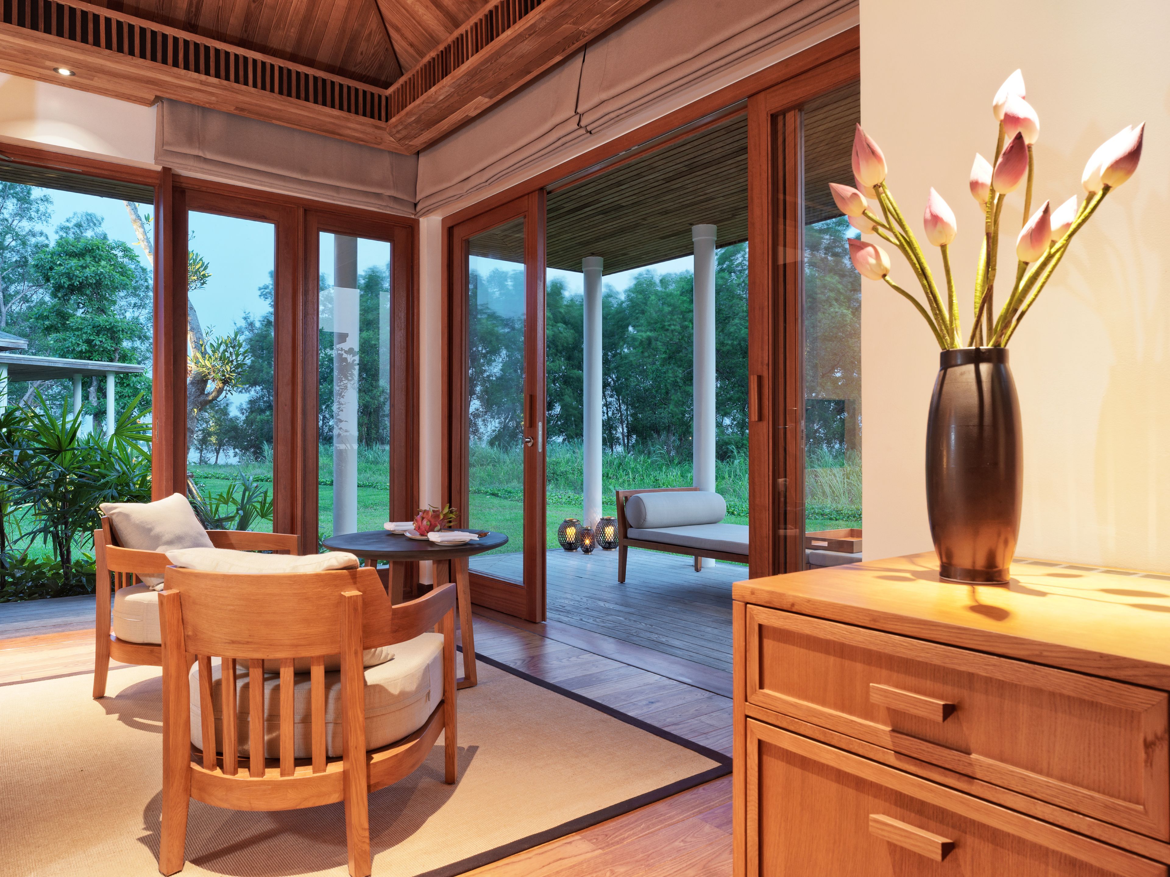 A modern interior with a wooden dining table, chairs, and a vase with flowers.