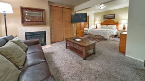 Een woonkamer met een open haard, een bank, een salontafel en een televisie.