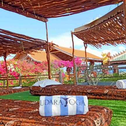 A serene outdoor yoga area with wooden benches and a stone wall.