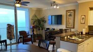 Une cuisine moderne avec un coin repas, un téléviseur fixé au mur et un balcon avec vue.