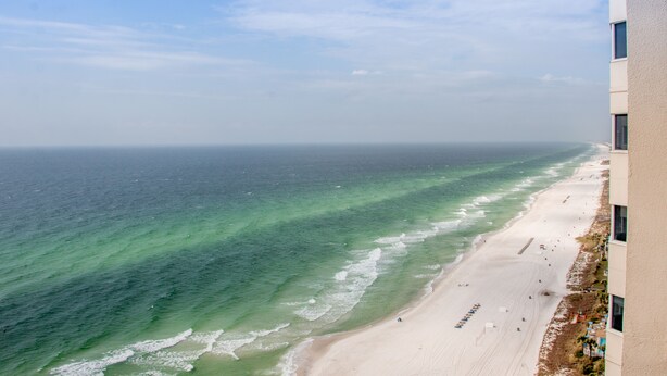 Une plage aux eaux cristallines et au rivage sablonneux, vue depuis un bâtiment.