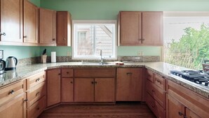 Una cocina con armarios de madera, encimeras de granito, una ventana y vistas al exterior.