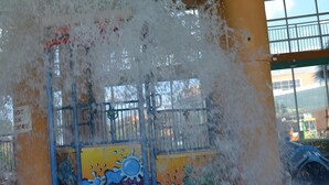 A water play area with a red fire hydrant, a colorful mural, and a green ceiling.
