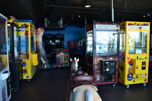 A row of arcade machines with colorful designs and a carousel in the foreground.