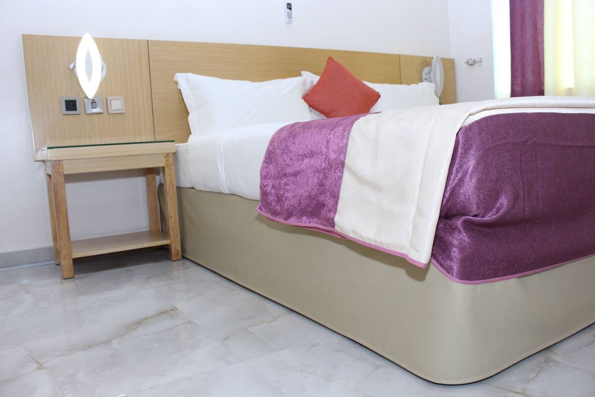 A neatly made bed with a wooden headboard, a bedside table, and a nightstand.