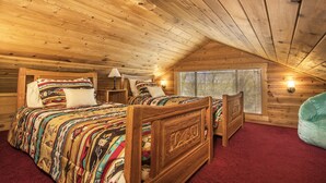 Une chambre de style rustique avec deux lits, des têtes de lit en bois, une moquette rouge et une fenêtre avec des stores.
