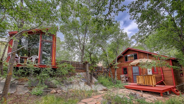 Un chalet rustique avec un toit de chaume et une terrasse en bois.