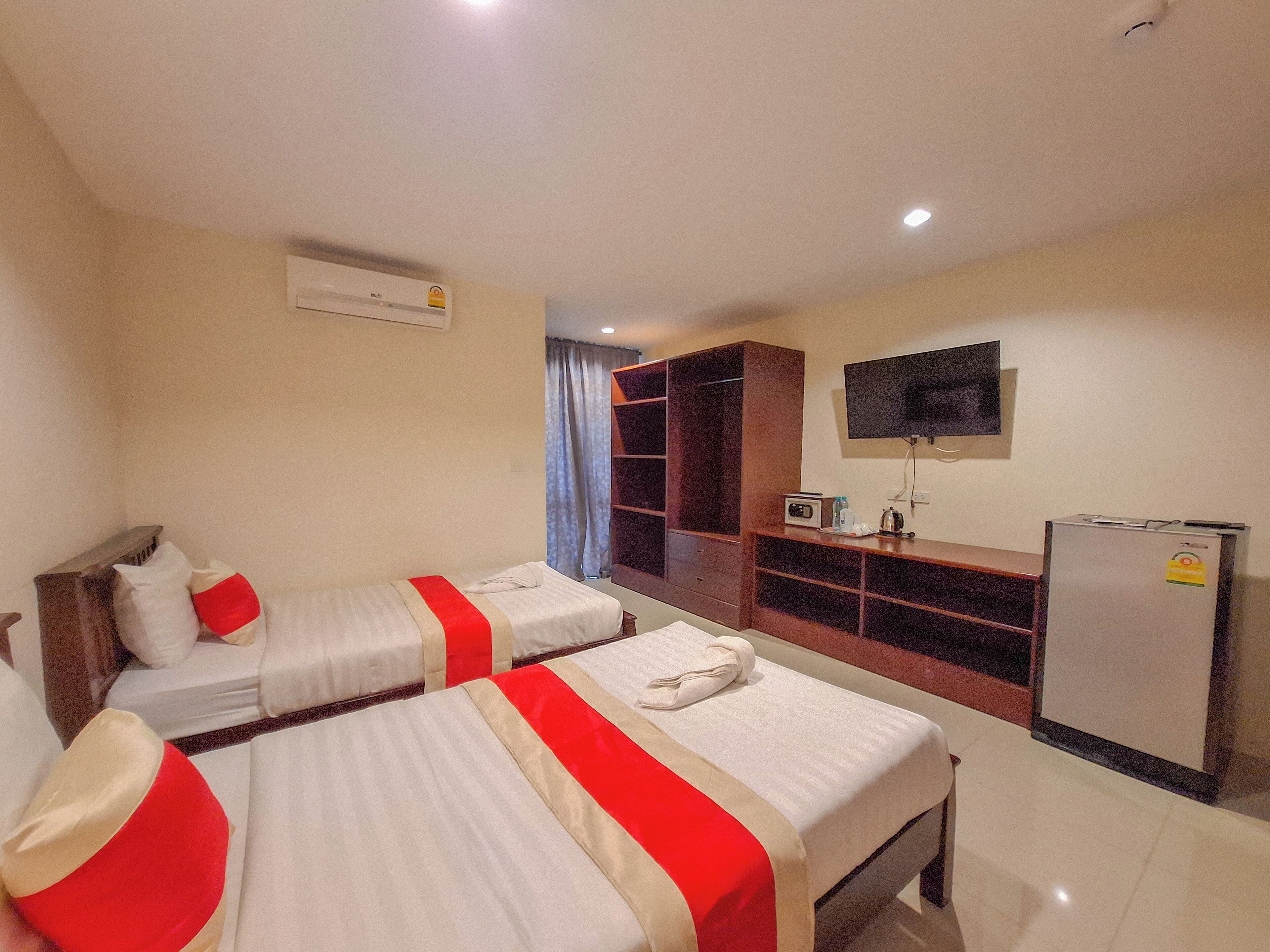 A hotel room with two beds, a TV, a refrigerator, and a wardrobe.