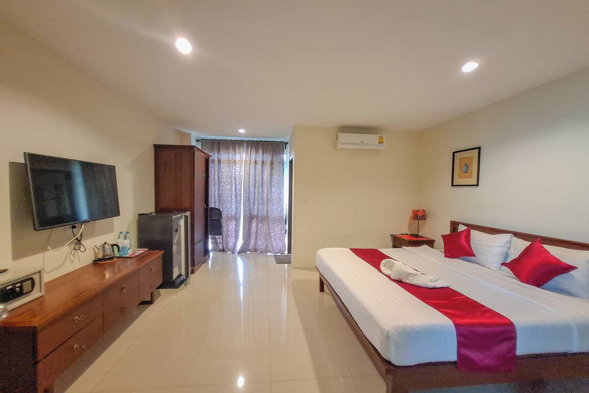 A hotel room with a bed, a TV, a desk, and a wardrobe.