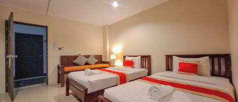 A hotel room with two beds, a door, and a nightstand with a lamp.