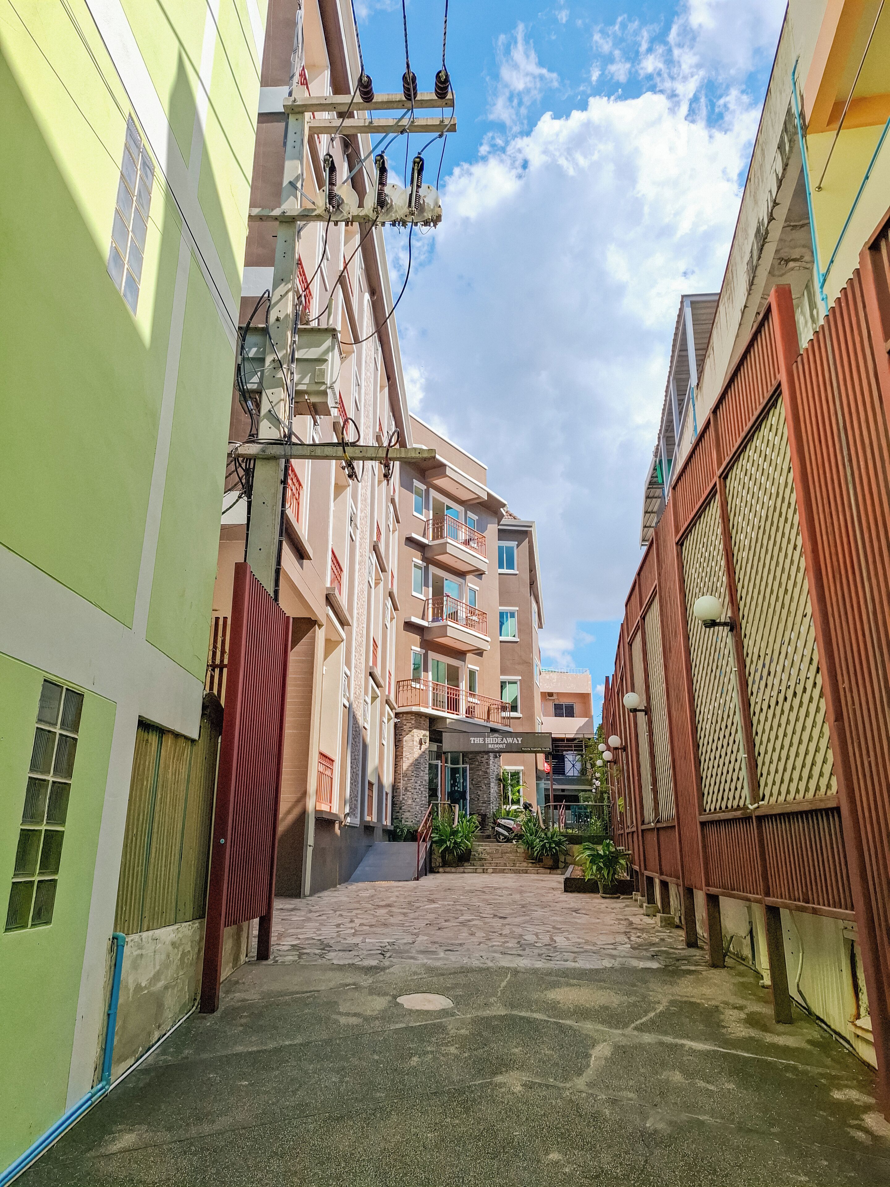 A narrow alleyway with buildings on either side, leading to a building with a sign that reads "The Hideaway Resort."