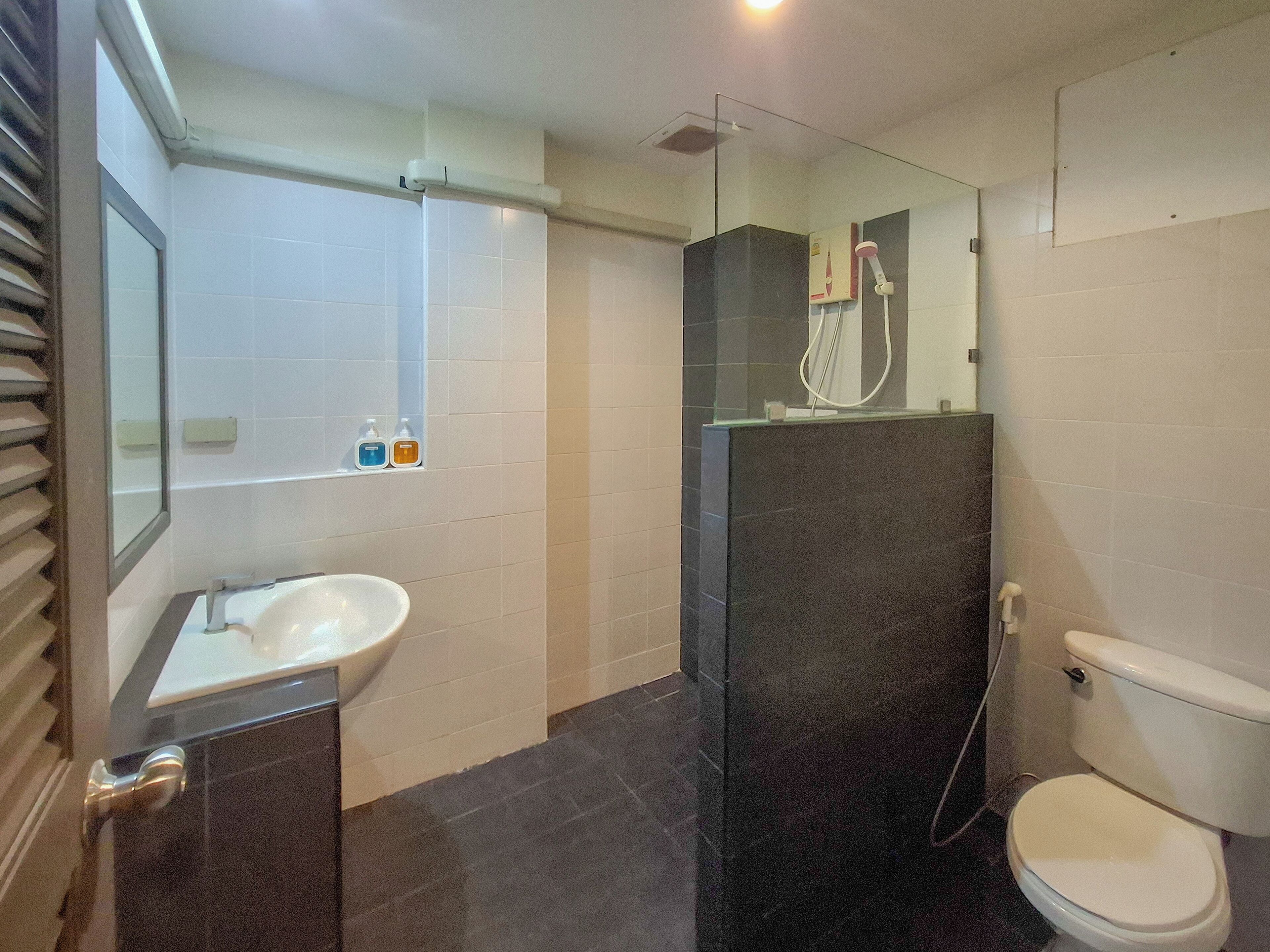 A modern bathroom with a glass shower enclosure, a white sink, and a toilet.
