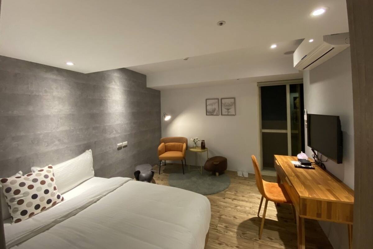 A modern bedroom with a large bed, a desk, and a chair.