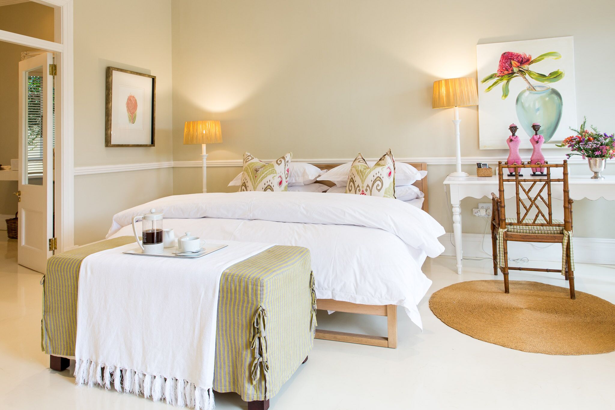 A neatly arranged bedroom with a bed, bedside tables, a chair, and a coffee table.